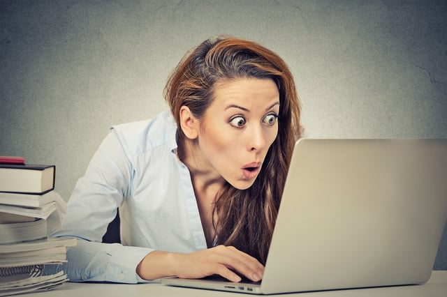 Portrait young shocked business woman sitting in front of laptop computer looking at screen isolated grey wall background. Funny face expression emotion feelings problem perception reaction.jpeg Portrait young shocked business woman sitting in front of laptop computer looking at screen isolated grey wall background. Funny face expression emotion feelings problem perception reaction.jpeg